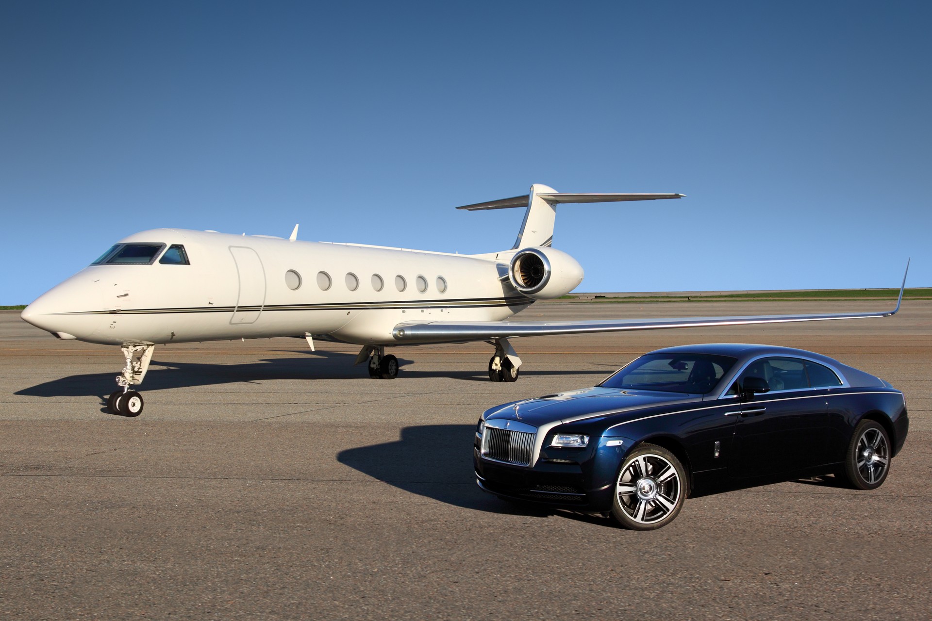 Private Gulfstream G550 executive airplane with Rolls Royce Wraith luxury car shown together at Sheremetyevo international airport.